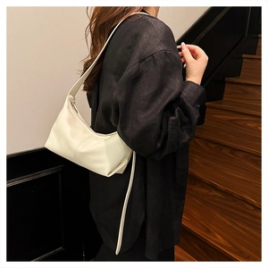 Close-up of a cream-colored leather hobo bag worn by a model on a shoulder strap