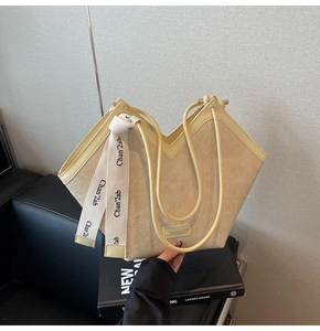 Detail of a beige tote bag with V-shaped cut design and textured leather with ribbon strap