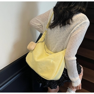 Detail of light yellow hobo bag with cat embroidery and plush kitten charm accessory