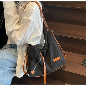 Detail of black tote bag with brown straps and matching round coin purse on a model