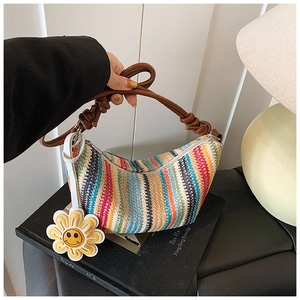 Detail of colorful woven shoulder bag with brown leather strap and sunflower charm