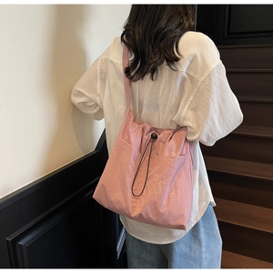 Detail of pink drawstring crossbody bag with adjustable strap for daily commute and leisure