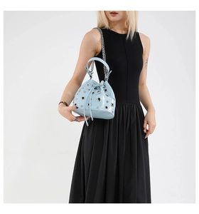 Detail of light blue bucket bag with metal hollow rivets and silver chain strap