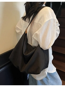 Grande borsa tote minimalista in tela nera per donna con dettagli in pelle su una modella