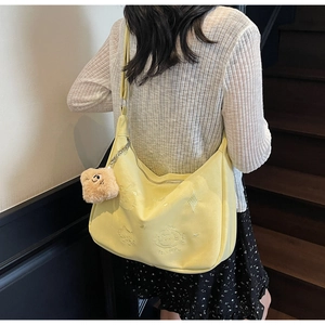Detail of yellow canvas crossbody bag with cute cat embroidery and bear charm