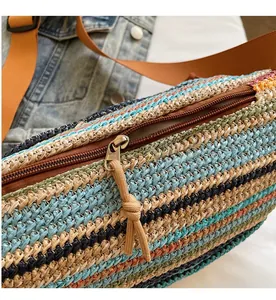 Detailed close-up of smooth bronze zipper and woven strap on colorful straw bag