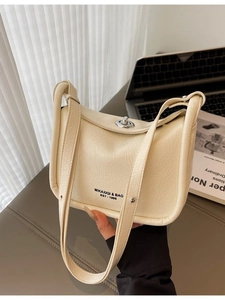 Beige faux leather shoulder bag with vintage silver buckle in an office setting