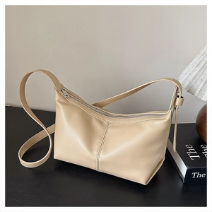 Detail of adjustable leather strap and metal zipper on beige crossbody dumpling bag