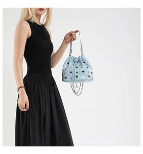 Detail of light blue bucket bag featuring silver studs and delicate hanging chain