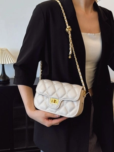 Cream quilted crossbody bag with gold chain and metal ball adjustment shown on model