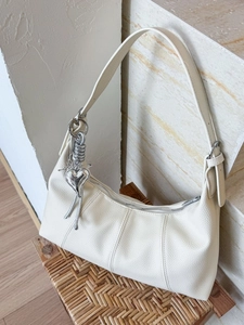 Minimalist beige crescent moon bag in pebbled leather with silver heart charm decoration