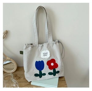 Detail view of canvas tote bag with drawstring closure and floral tulip embroidery