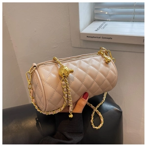 Détail du sac cylindrique matelassé beige avec chaîne dorée et breloque boule