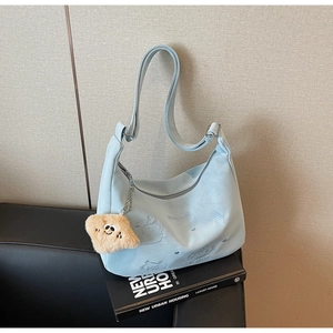 Detail of light blue embroidered crossbody bag with cute yellow cloud pendant on books