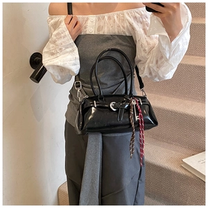 Detail of black glossy leather handbag with silver crescent buckle and woven rope charms