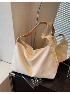 Borsa tote in tela beige con manici in pelle marrone mostrata su una superficie riflettente