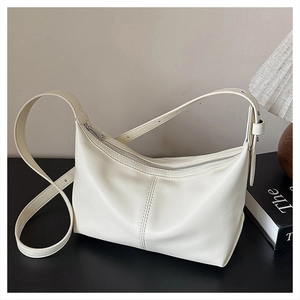 Detail of cream leather crescent bag with adjustable strap and decorative stitching