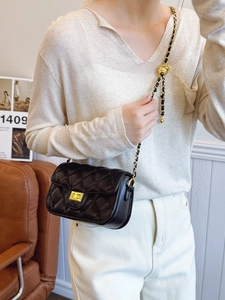 Quilted leather flap bag with gold chain strap and adjustable ball on a model