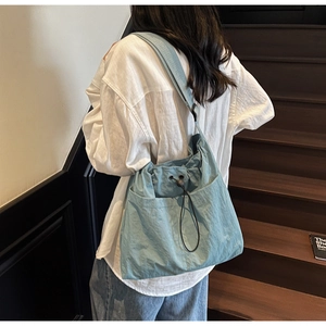Detail of blue drawstring bucket bag featuring side pocket and textured nylon fabric