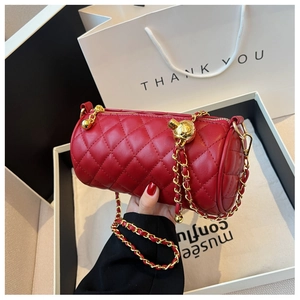Détail d'un sac cylindre matelassé rouge avec chaîne dorée et bille de réglage
