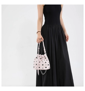 Detail of pink rivet bucket bag with silver studs and chain strap on black dress