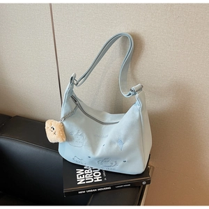 Detail of mint green suede bag featuring cute cartoon embroidery and plush bread charm