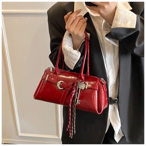 Detail of dark red patent leather handbag with silver horseshoe buckle and heart charms