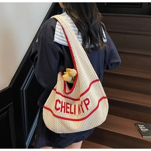 Detail of knit shoulder tote bag in off-white with red jacquard lettering on a model