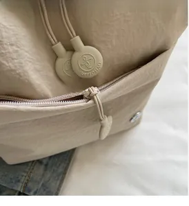 Detail of premium beige canvas bag featuring a smooth metal zipper and branded puller