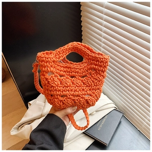 Detail of bright orange hand-knitted bucket bag showing hollow texture and beige lining