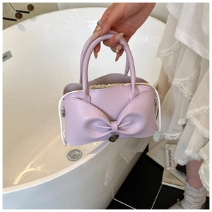 Détail d'un sac seau lavande avec nœud papillon, pendentif en cœur et cordon de serrage