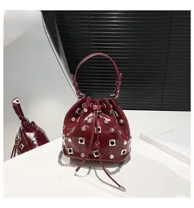 Close-up of wine red bucket bag with metallic studs and drawstring closure