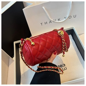Détail du sac cylindre en cuir matelassé rouge avec chaîne dorée et boucle à bille