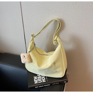 Detail of light yellow canvas crossbody bag with animal embroidery and plush face pendant
