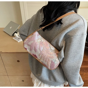 Detail of sequin embroidered shoulder bag with pink floral patterns and leather strap