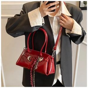 Detail of red patent leather handbag with metallic lock charm and striped silk scarf