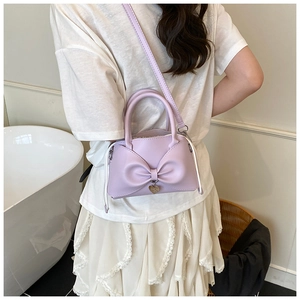 Vista posteriore di una modella con borsa a secchiello lavanda, fiocco e ciondolo cuore