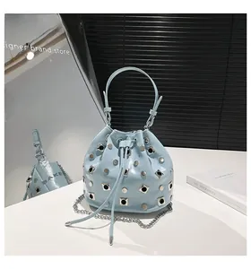 Close-up of light blue rivet bucket bag with silver studs and drawstring closure