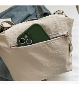 Detail of canvas crossbody bag with front zipper pocket and wide printed strap