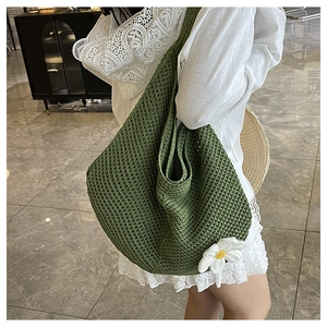 Détail d'un sac hobo en tricot vert avec des motifs de fleurs de marguerite au bas