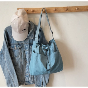 Detail of light blue bucket bag with drawstring pockets and adjustable wide strap