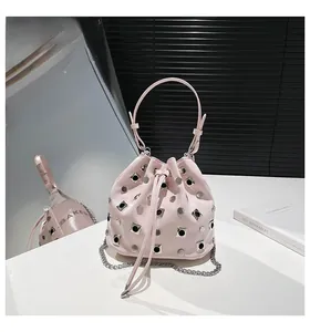 Detail of light pink bucket bag with silver metal studs and metallic chain strap