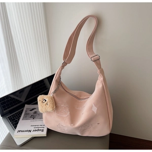 Close-up of pink canvas hobo bag featuring cartoon cat embroidery and plush pendant charm