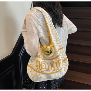 Detail showing the cream knitted mesh tote with contrasting yellow trim and letter pattern