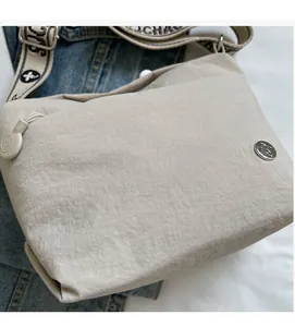 Detailed view of casual beige canvas crossbody bag with jacquard wide strap and metal logo