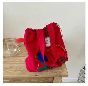 Close-up of red canvas tote bag with floral tulip embroidery and drawstring closure detail