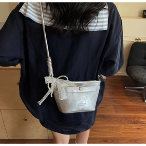 Detail of silver metallic crossbody bag featuring pleated texture and pearl chain
