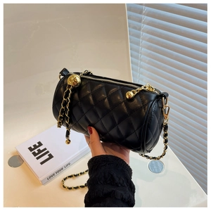 Détail du sac cylindre en cuir noir matelassé avec chaîne dorée et bille de réglage