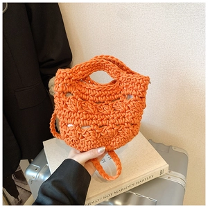 Detail of orange hand-woven bucket bag with intricate hollow texture and cotton rope straps
