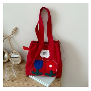 Close-up of red canvas tote bag with drawstring closure and tulip embroidery detail
